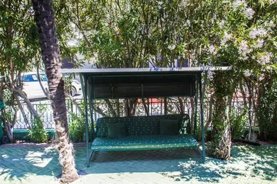a green bench sitting under a canopy under trees at Villa Elkom App 2 in Ulcinj