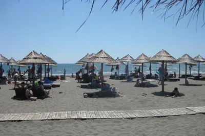 a group of people laying on a beach with umbrellas at Villa Elkom, App.9 in Ulcinj
