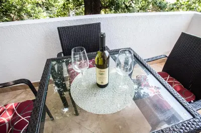 a glass table with a bottle of wine and two glasses at Villa Elkom, App 16 in Ulcinj