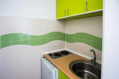 a small kitchen with a sink and green and white tiles at Villa Elkom, App.17 in Ulcinj