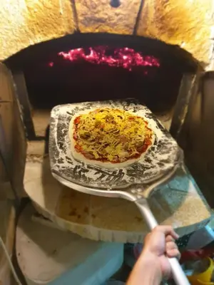a person taking a pizza out of an oven at House Carpe Diem with the best sea view in Masline