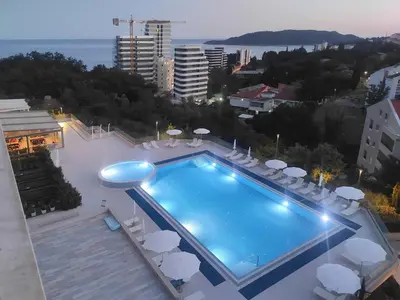 a swimming pool with chairs and umbrellas on a building at Status-M Apartments 179 in Becici