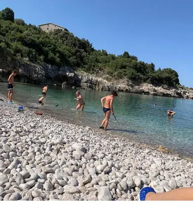 a group of people playing in the water on a rocky beach at White Star Apartments in Utjeha