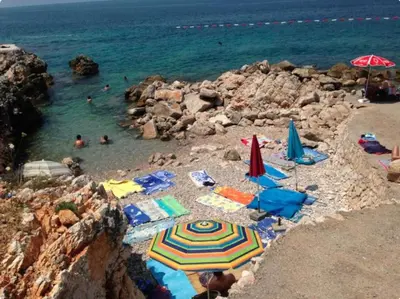 a beach with umbrellas and people in the water at Villa Lyudmila in Utjeha