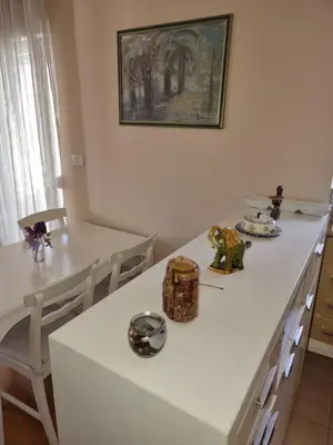 a kitchen with white counters and a table and chairs at Sunny City - City Kvart in Podgorica