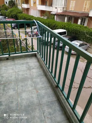 a green railing next to a sidewalk with a parking lot at Apartman Potkošljun in Budva