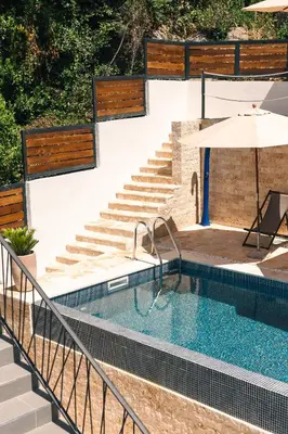 a swimming pool with stairs and an umbrella at CASA BIANCA & Spa 2 in Ulcinj