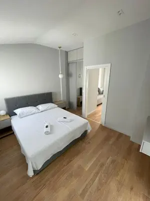 a bedroom with a large white bed and wooden floors at Lungomare Apartments in Petrovac na Moru