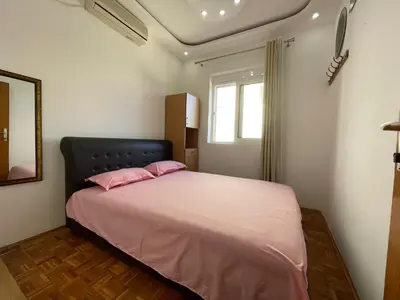 a bedroom with a bed with pink pillows and a window at Aprtmani centar 2 in Ulcinj